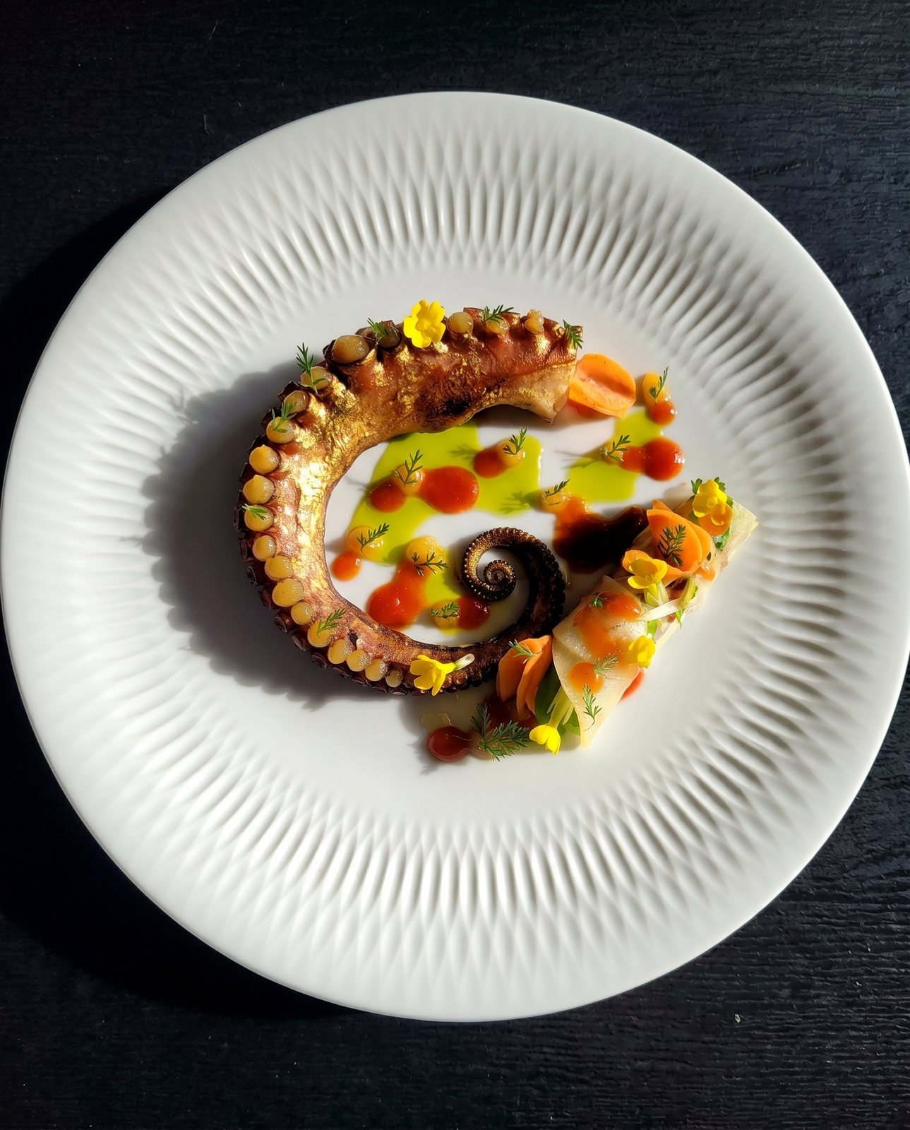 Kunstvoll angerichteter Oktopus mit Gemüse und essbaren Blüten